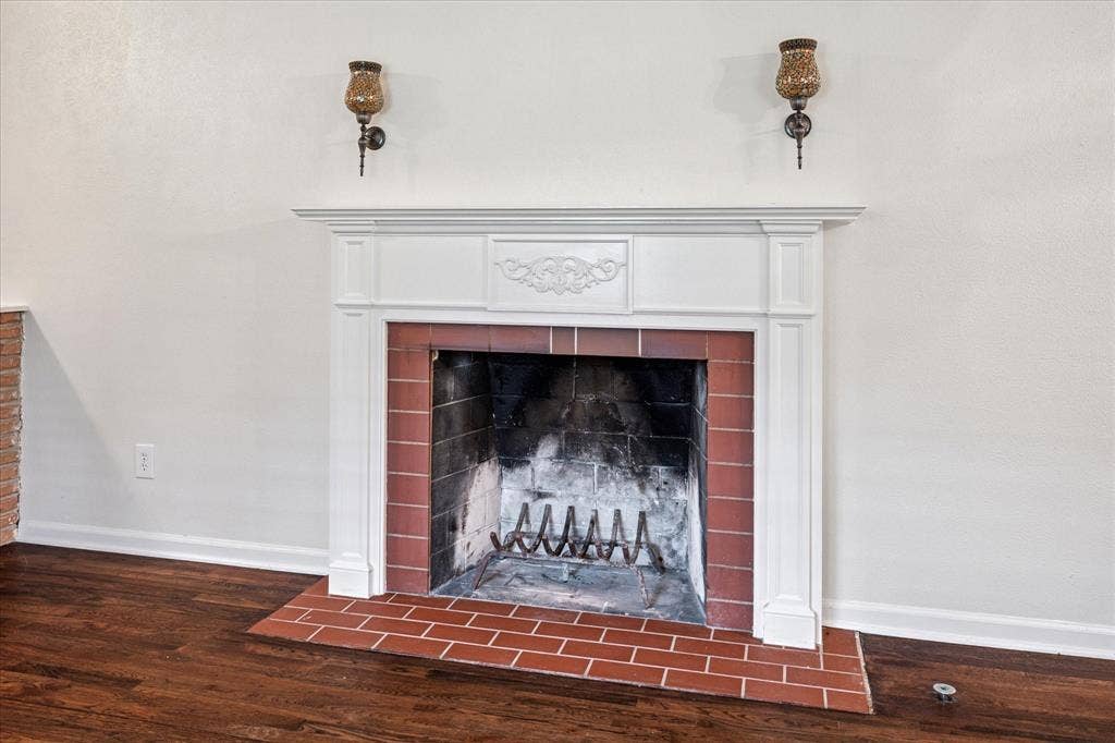 1725 Mapleton Drive, Dallas, TX 75228 iving room woodburning fireplace with mantle, sconces, brick hearth, and gas starter.