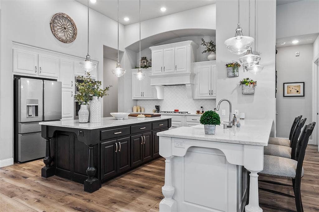 1113 12th Street, Argyle, TX 76226 Kitchen featuring appliances with stainless steel finishes, a kitchen island with sink, pendant lighting, hardwood / wood-style flooring, and white cabinets