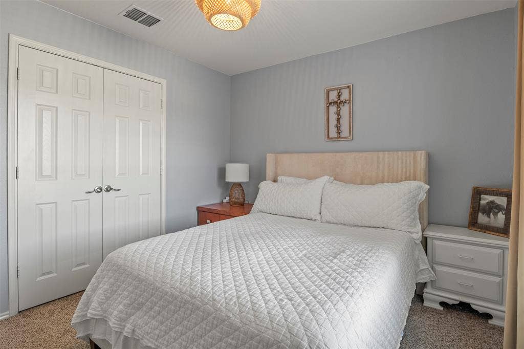 Neutral gray wall paint, textured carpet flooring, bi-fold panel doors, and a decorative ceiling light fixture