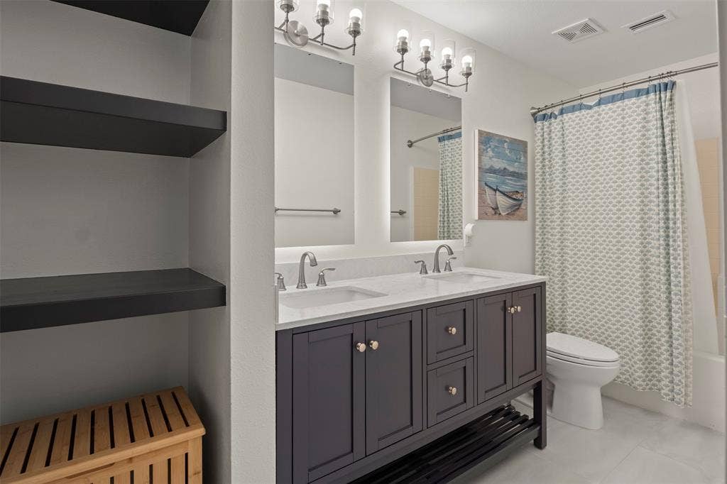 Dual vanity with white countertop, chrome fixtures, and dark cabinetry