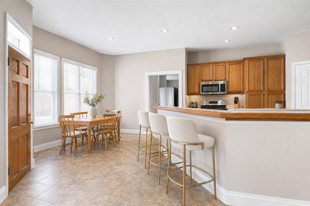 1908 Meadow Springs Drive, Haslet, TX 76052 Kitchen and dining area featuring wood-finish cabinetry, stainless steel microwave, tile flooring, and recessed lighting