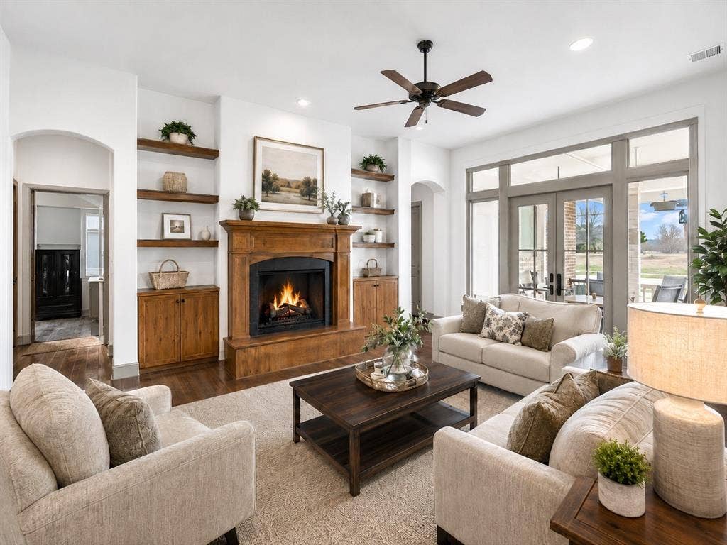 1908 Meadow Springs Drive, Haslet, TX 76052 Living area with fireplace featuring a wood mantel, built-in shelving, wood-finish flooring, and double glass-paneled doors with transom windows