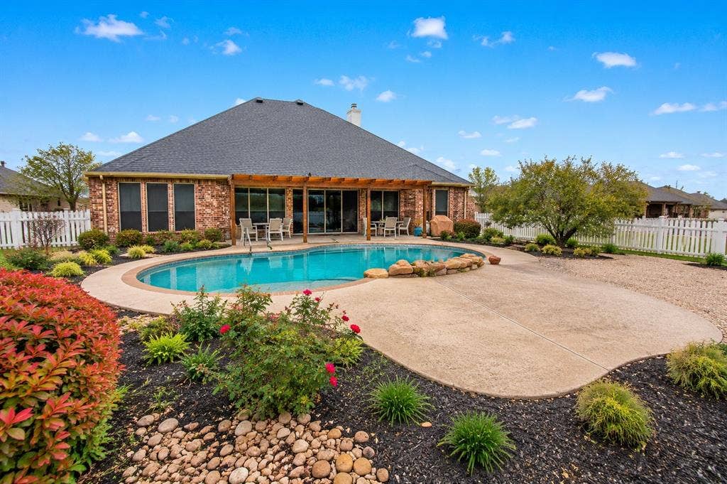 1908 Meadow Springs Drive, Haslet, TX 76052 Custom-shaped swimming pool with an expansive concrete patio and surrounding landscape
