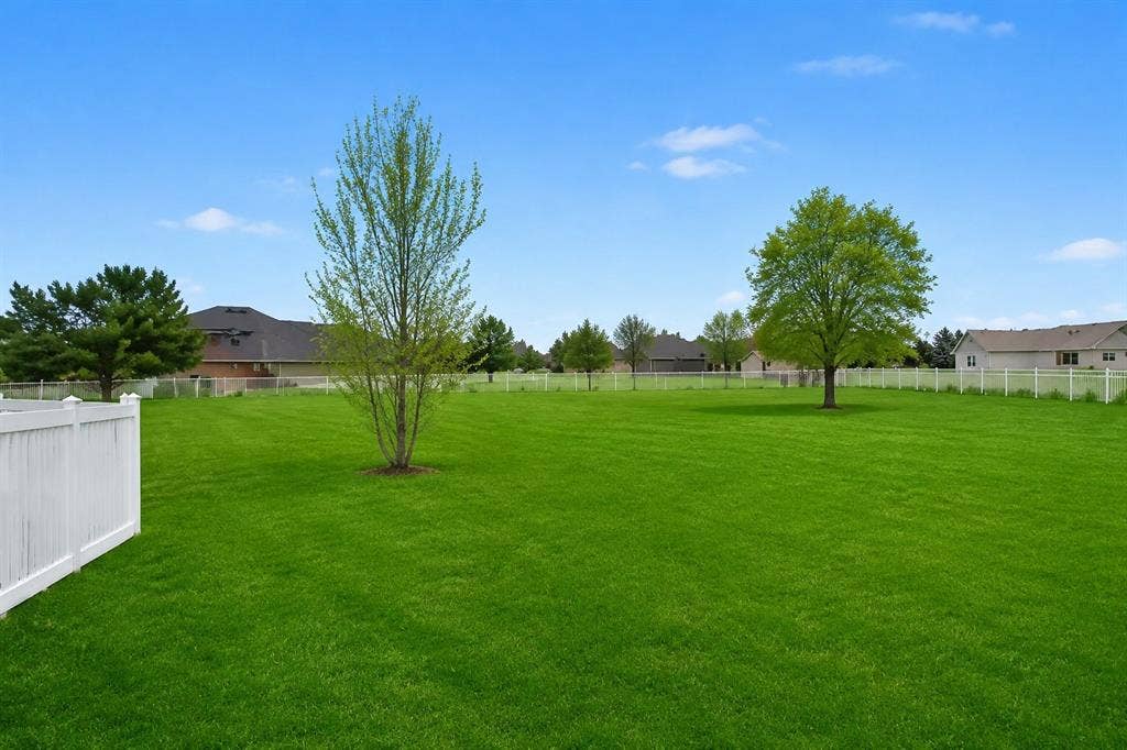 1908 Meadow Springs Drive, Haslet, TX 76052 Expansive lawn area featuring a white perimeter fence, mature trees, and a clear blue sky