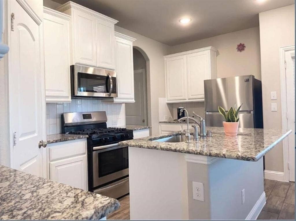 632 Redwood Drive, Greenville, TX 75402 Kitchen featuring white cabinetry, stainless steel appliances, granite countertops, and subway tile backsplash