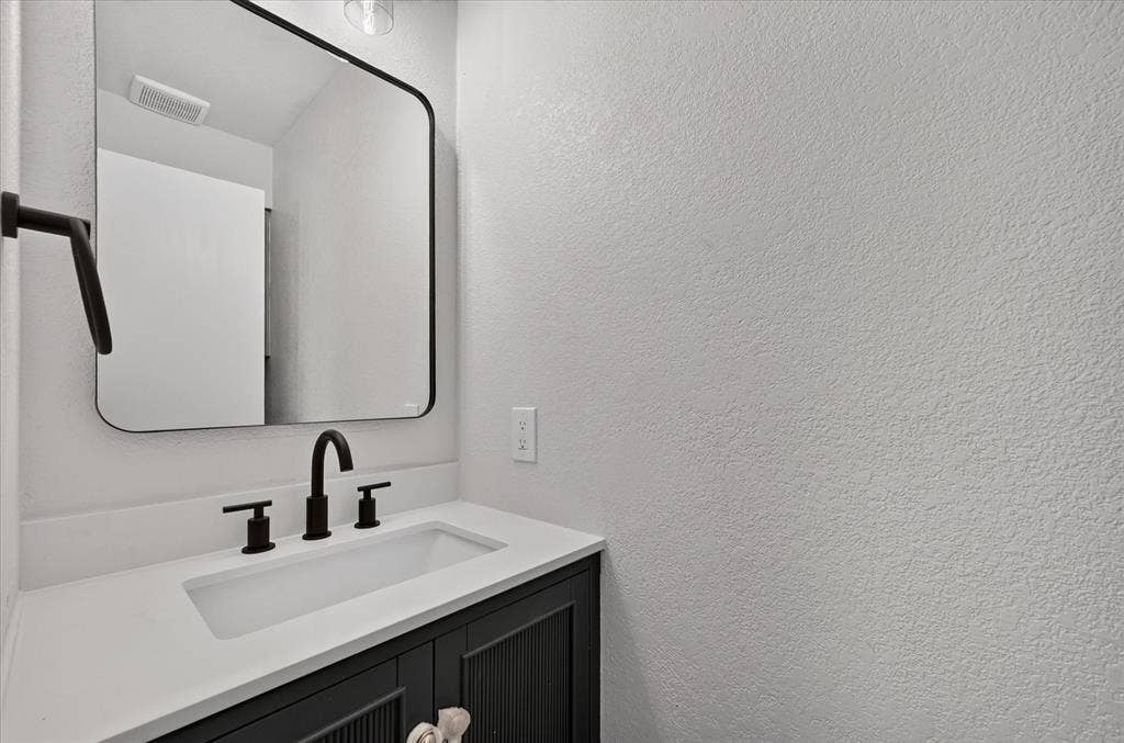 1528 Estrella Drive, Plano, TX 75074 Powder Room / Half Bath. Vanity with white countertop, integrated rectangular sink, and matte black fixtures