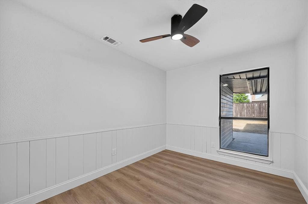 1528 Estrella Drive, Plano, TX 75074 Recessed window with black trim, wood-finish flooring, white paneled wainscoting, and a contemporary ceiling fan with integrated lighting