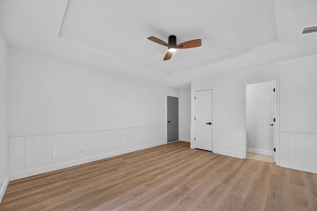 1528 Estrella Drive, Plano, TX 75074 Tray ceiling, ceiling fan with wood-finish blades, wood-finish flooring, white wainscoting, white doors with matte black hardware