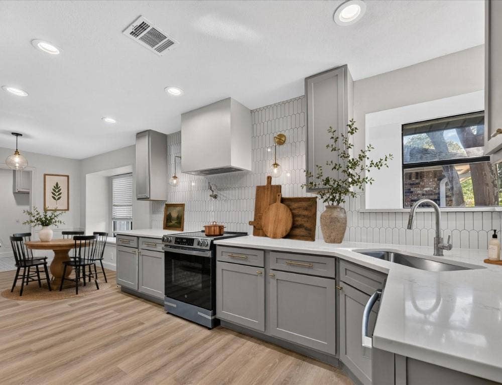 1528 Estrella Drive, Plano, TX 75074 Kitchen featuring taupe cabinetry, white countertops, wood-finish flooring, a stainless steel range, and a white picket tile backsplash