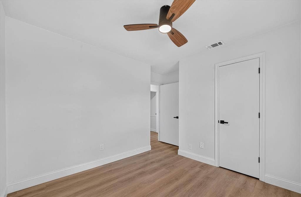 1528 Estrella Drive, Plano, TX 75074 Wood-finish flooring with white baseboards, modern ceiling fan with wood-tone blades, and white doors with matte black hardware