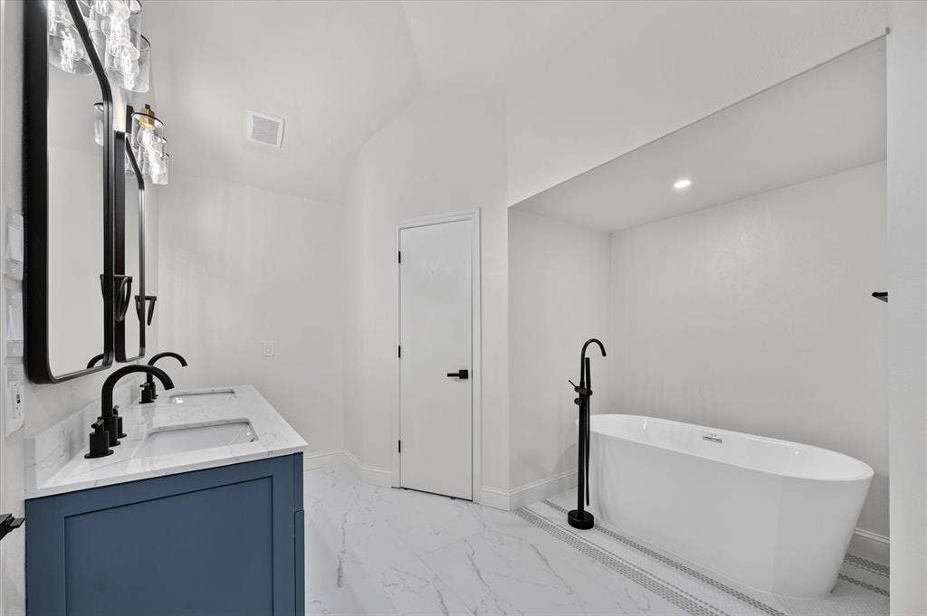 1528 Estrella Drive, Plano, TX 75074 Dual vanity with a blue cabinet, rectangular sinks, and black fixtures