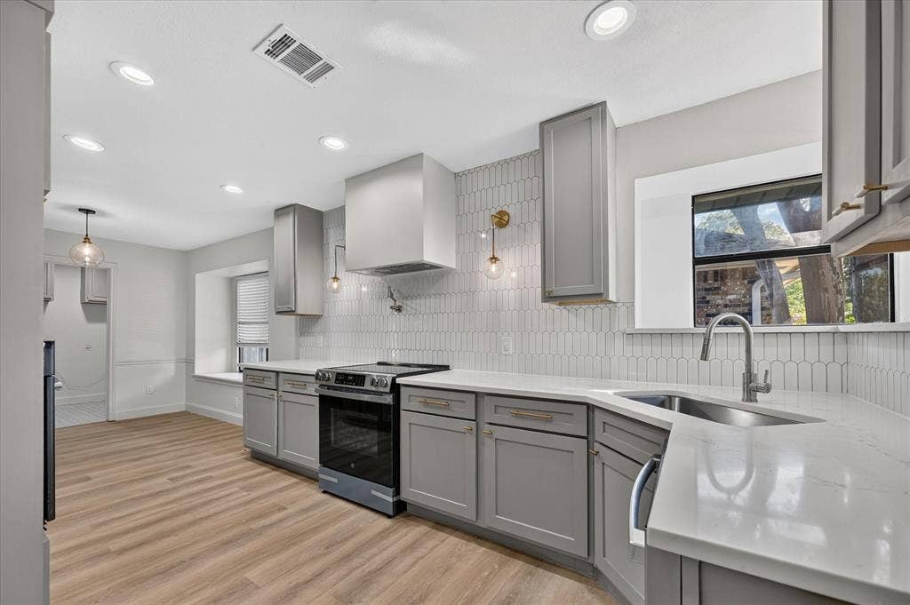 1528 Estrella Drive, Plano, TX 75074 Kitchen featuring taupe cabinetry, white countertops, wood-finish flooring, a stainless steel range, and a white picket tile backsplash