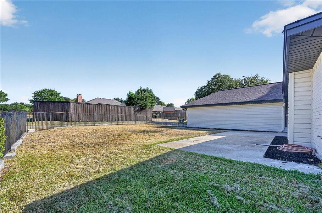 1528 Estrella Drive, Plano, TX 75074 Expansive backyard featuring a partial wood privacy fence, partial metal fencing, concrete patio, and mature trees