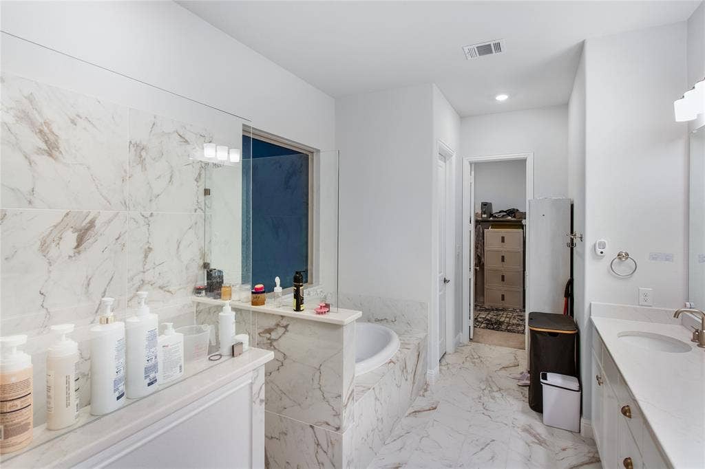 1531 20th street, Argyle, TX 76226 Spacious bathroom featuring a built-in soaking tub, a dual vanity with undermount sinks, and marble-look tile flooring