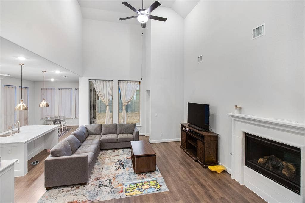 1531 20th street, Argyle, TX 76226 Open-concept living space featuring soaring ceilings with ceiling fan, wood-finish flooring throughout, and a gas fireplace with surround