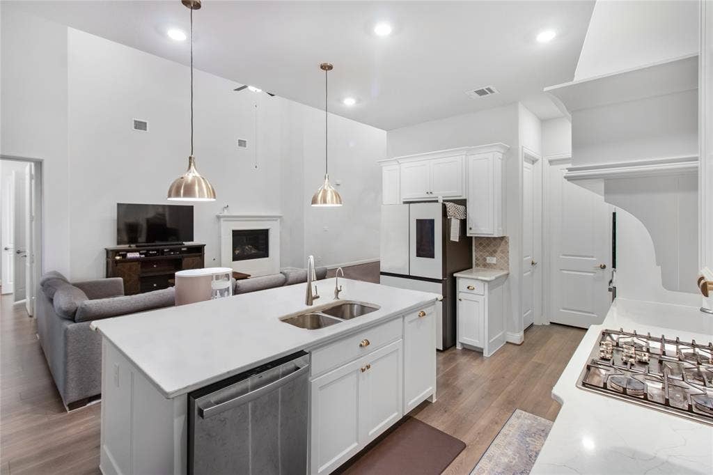 1531 20th street, Argyle, TX 76226 Contemporary kitchen and living spaces featuring white cabinetry, quartz countertops, and stainless steel appliances including a gas cooktop and built-in refrigerator
