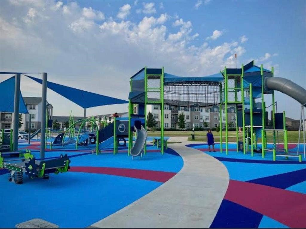 7204 Running Iron Trail, Sachse, TX 75048 Integrated playground featuring multiple slides, climbing structures, shade sails, and a patterned soft-fall surface