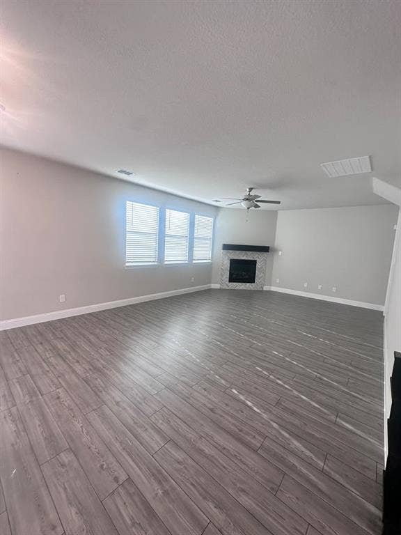 7204 Running Iron Trail, Sachse, TX 75048 Spacious interior with wood-finish flooring, multiple windows with blinds, a ceiling fan, and a fireplace with a mantel