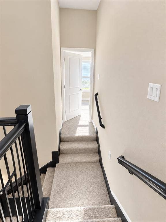 7204 Running Iron Trail, Sachse, TX 75048 Carpeted stairs with black handrails and balusters, leading to an open doorway