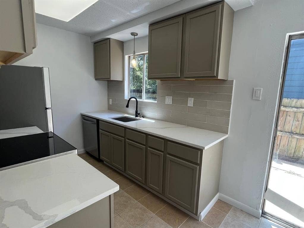9515 Aberdeen Way, Austin, TX 78753 Contemporary kitchen featuring light-toned cabinetry, white countertops, tile backsplash, and a black faucet