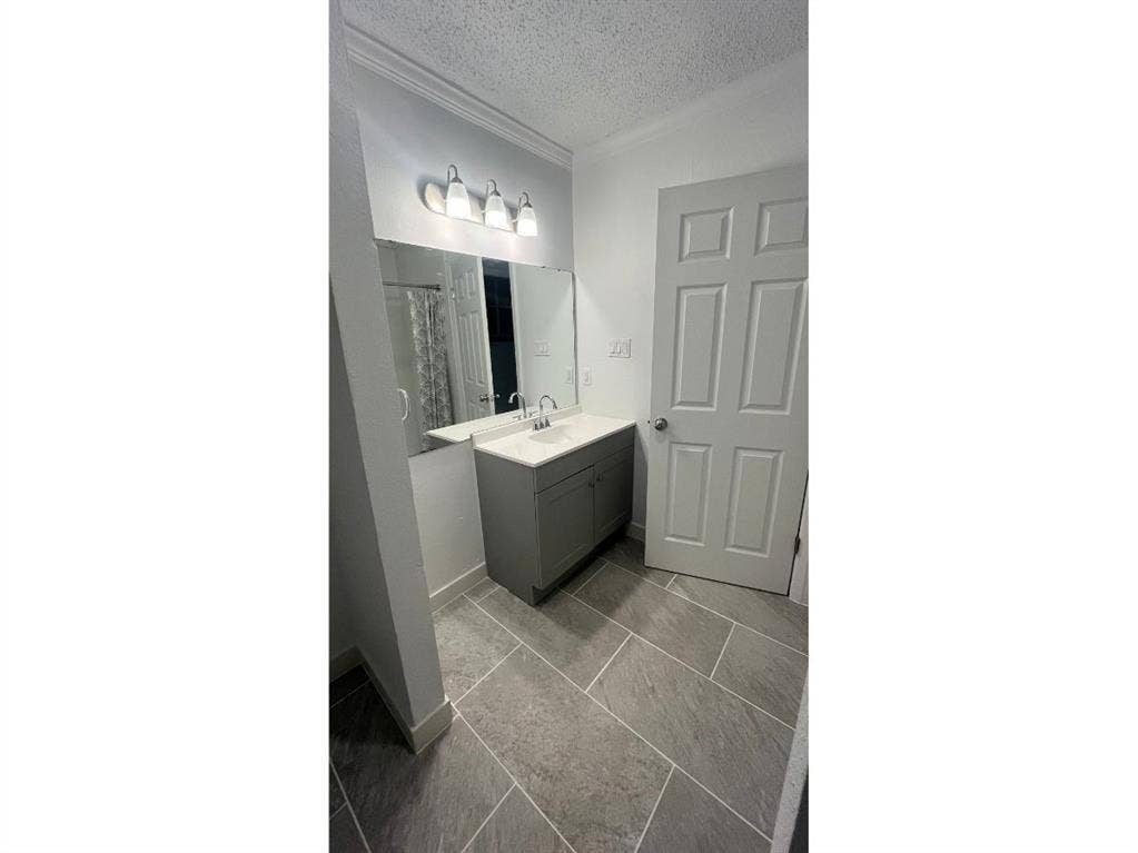 9515 Aberdeen Way, Austin, TX 78753 Bathroom featuring large format tile flooring, single vanity with integrated sink, wall-mounted mirror, and multi-bulb light fixture