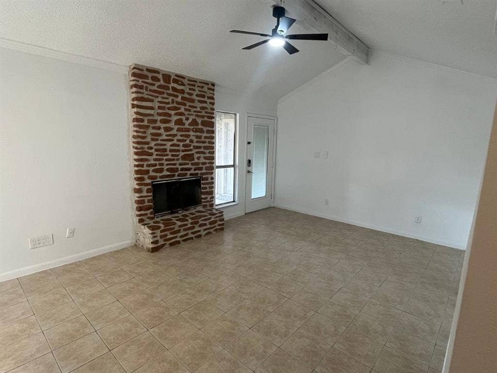 9515 Aberdeen Way, Austin, TX 78753 Stone-clad fireplace feature with an integrated media niche, vaulted ceiling with exposed wood beam, ceiling fan with integrated lighting, and tile flooring