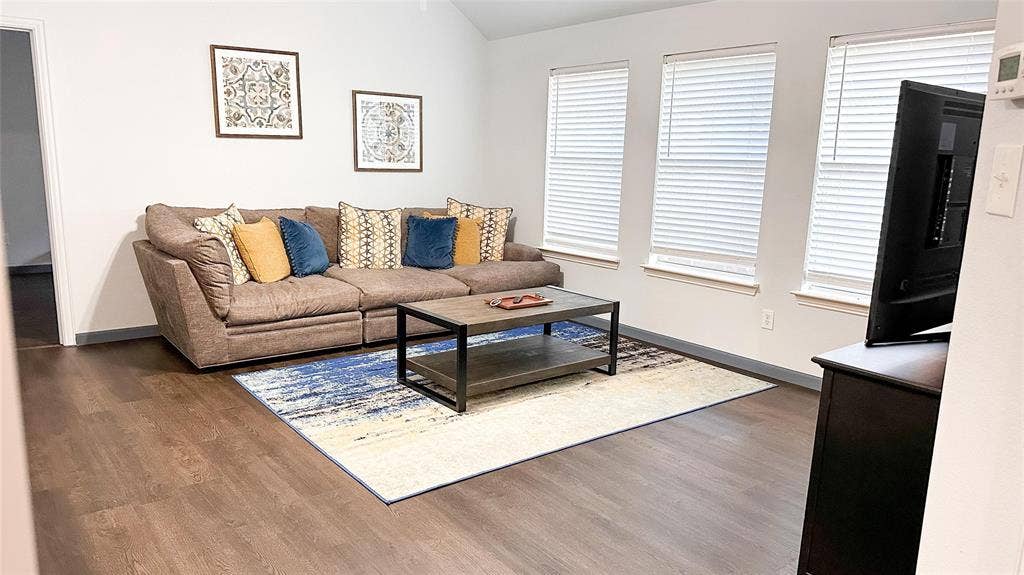 12146 Gonzales Drive, Frisco, TX 75035 Living room featuring wood finished floors, baseboards, and lofted ceiling