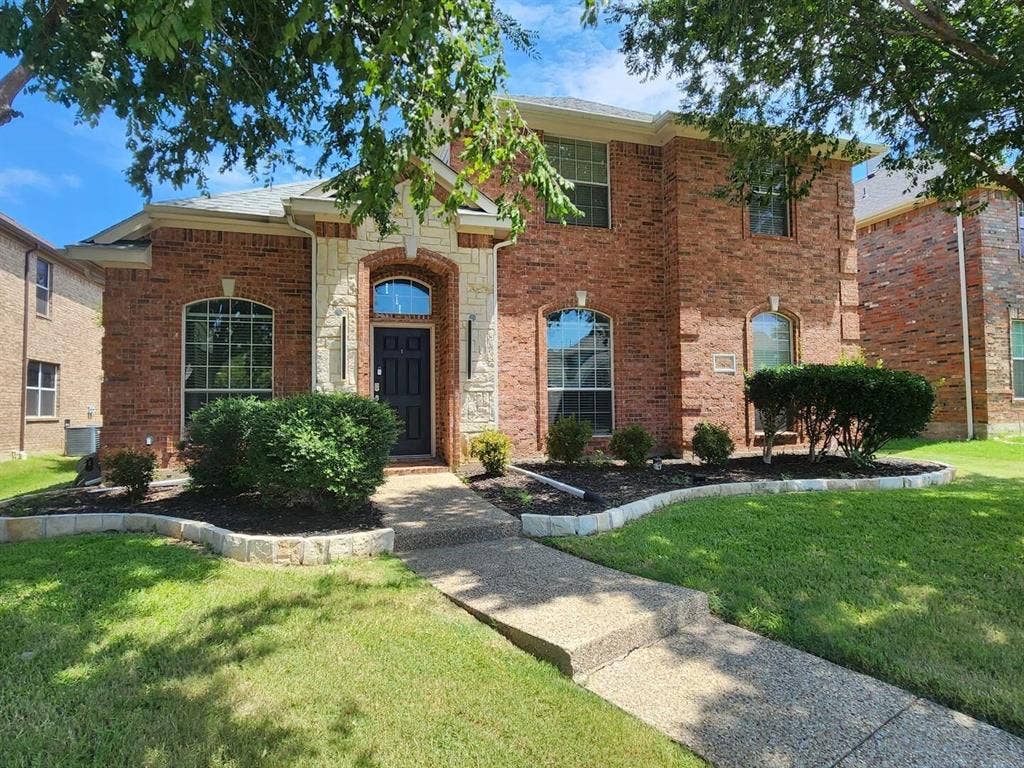 12146 Gonzales Drive, Frisco, TX 75035 View of front of home with brick siding, a front lawn, and cooling unit