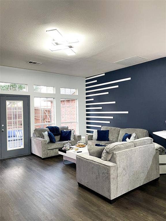 12146 Gonzales Drive, Frisco, TX 75035 Living room featuring dark wood-style floors, healthy amount of natural light, and a textured ceiling