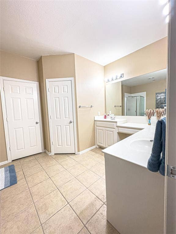 12146 Gonzales Drive, Frisco, TX 75035 Full bath featuring tile patterned floors, a stall shower, vanity, and baseboards