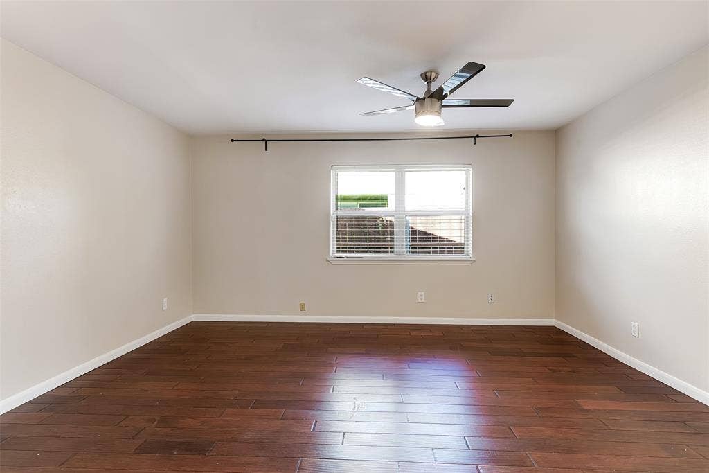 925 Lombardy Drive, Plano, TX 75023 Spacious room with wood-finish flooring, neutral-toned walls, a window with horizontal blinds, and a ceiling fan with integrated lighting