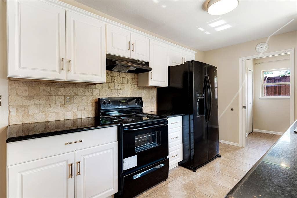 925 Lombardy Drive, Plano, TX 75023 White cabinetry with brushed nickel hardware, black countertops, tile backsplash, black range, and side-by-side refrigerator