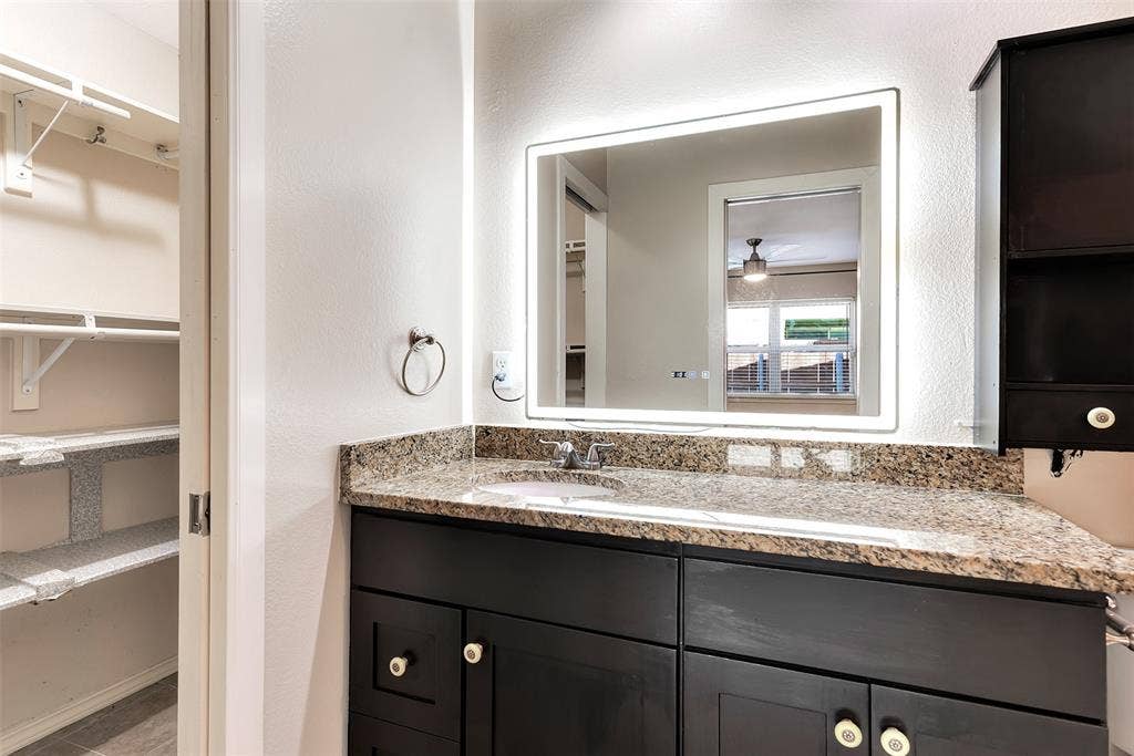 925 Lombardy Drive, Plano, TX 75023 Bathroom vanity with a granite countertop, integrated sink, and modern illuminated mirror