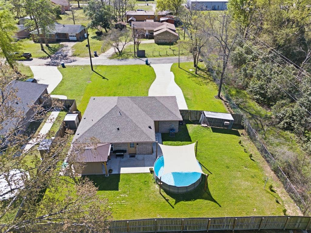 213 Freeman Street, Lindale, TX 75771 Expansive fenced yard with a pool, shade sail, and two storage sheds