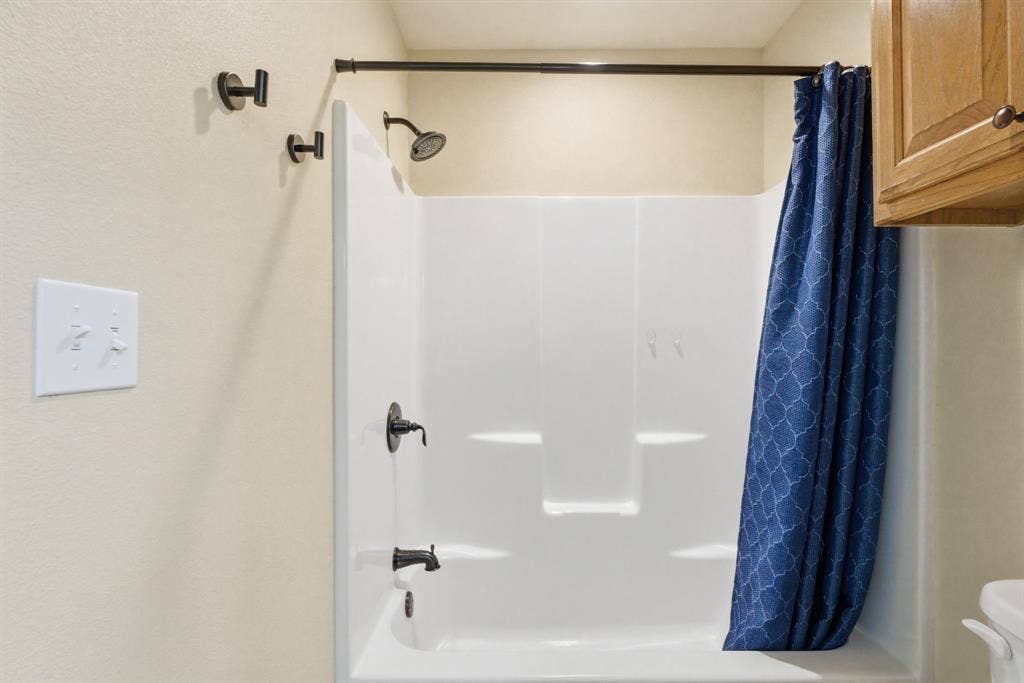213 Freeman Street, Lindale, TX 75771 White tub and shower combination with dark bronze fixtures
