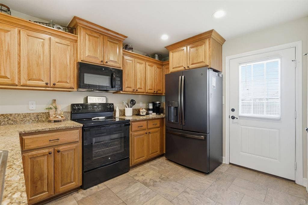 213 Freeman Street, Lindale, TX 75771 Kitchen featuring wood cabinetry, light-toned countertops, tile flooring, and integrated appliances