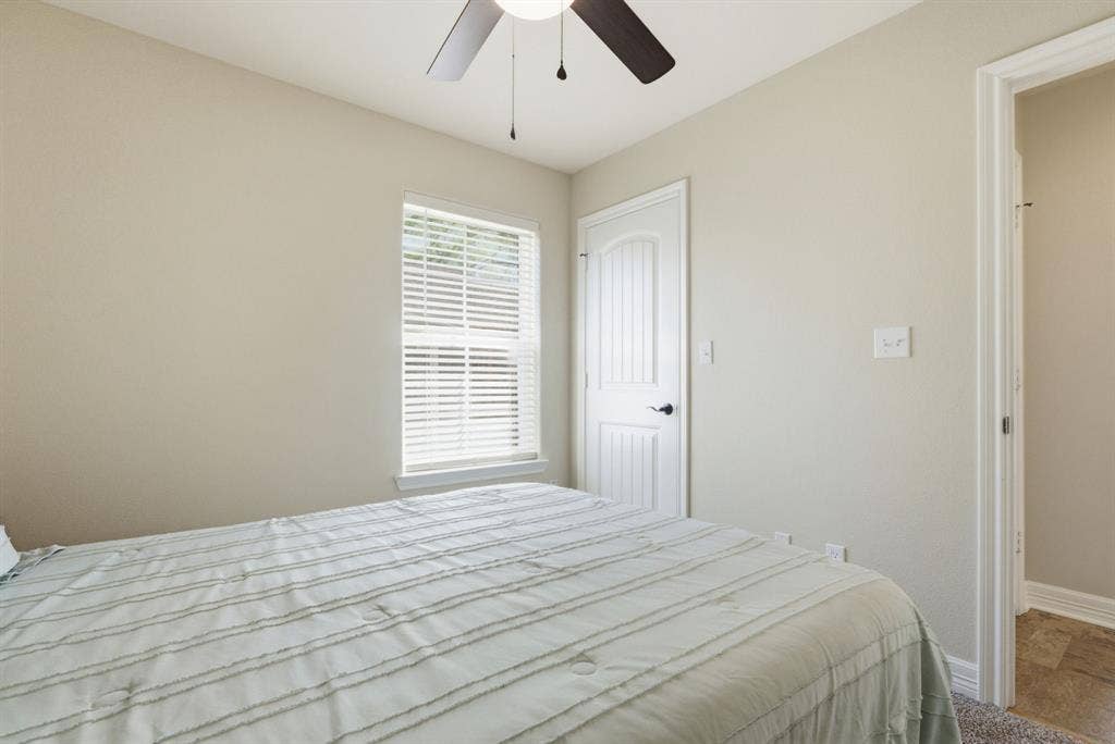 213 Freeman Street, Lindale, TX 75771 Ceiling fan with light fixture, window with blinds, white paneled door, and neutral-toned wall paint