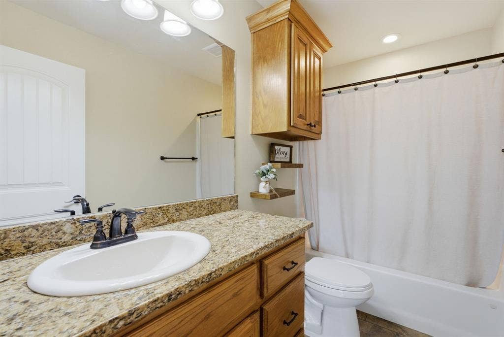 213 Freeman Street, Lindale, TX 75771 Vanity with a granite-look countertop, integrated sink, and an oil-rubbed bronze finish faucet