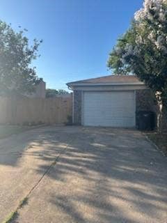 2805 Woodmont Trail, Fort Worth, TX 76133 Paved driveway leading to a single-car garage with brick siding and a wood privacy fence