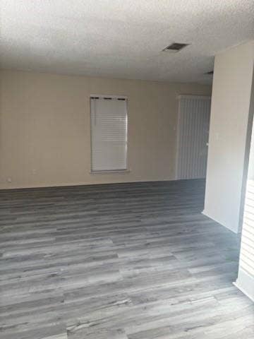 2805 Woodmont Trail, Fort Worth, TX 76133 Spacious room with gray wood-finish flooring, neutral wall tones, and a window with white blinds