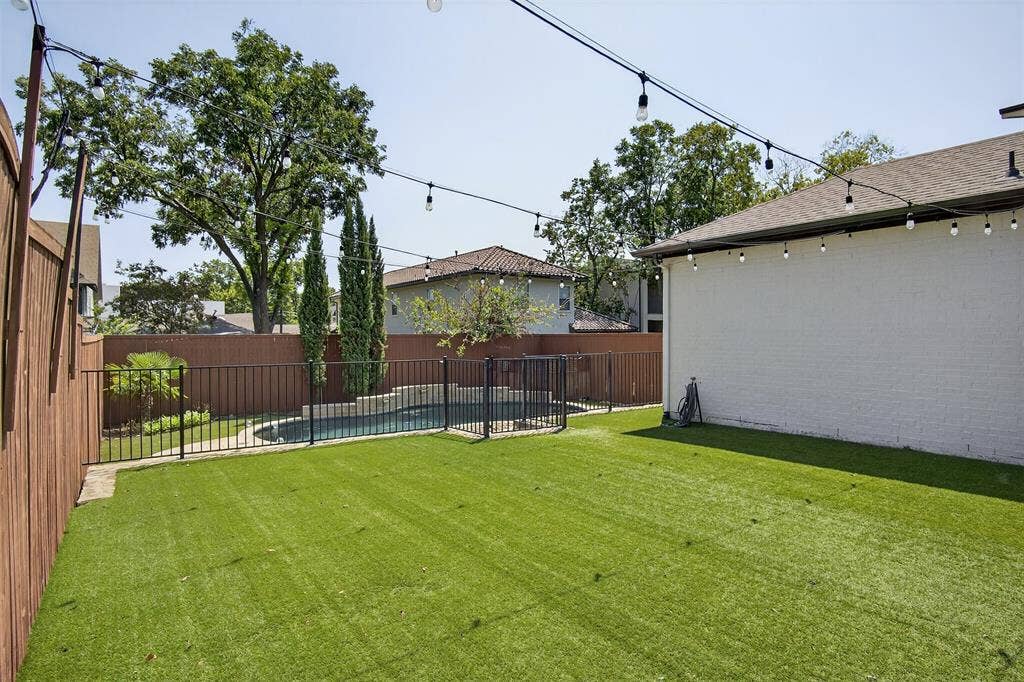 5328 Manett Street, Dallas, TX 75206 Expansive backyard featuring artificial turf, a fenced swimming pool, and string lighting