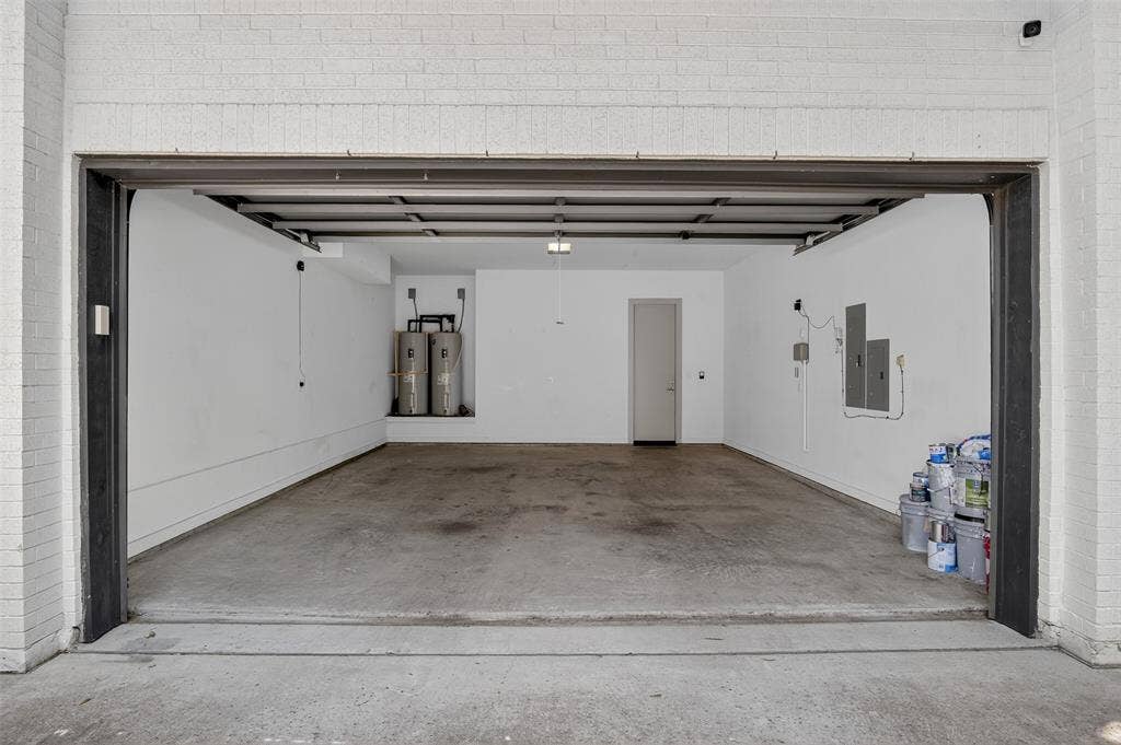 5328 Manett Street, Dallas, TX 75206 Garage with concrete flooring, white painted brick, and a built-in utility closet