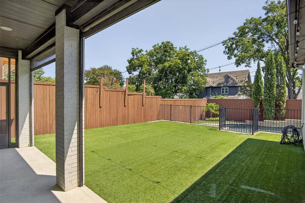 5328 Manett Street, Dallas, TX 75206 Expansive backyard featuring artificial turf, a wood privacy fence, and a black metal pool fence
