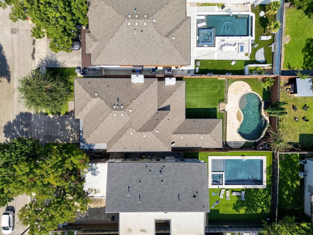 5328 Manett Street, Dallas, TX 75206 Expansive backyard featuring a custom-shaped swimming pool, surrounding stone-finish patio, and artificial turf lawn