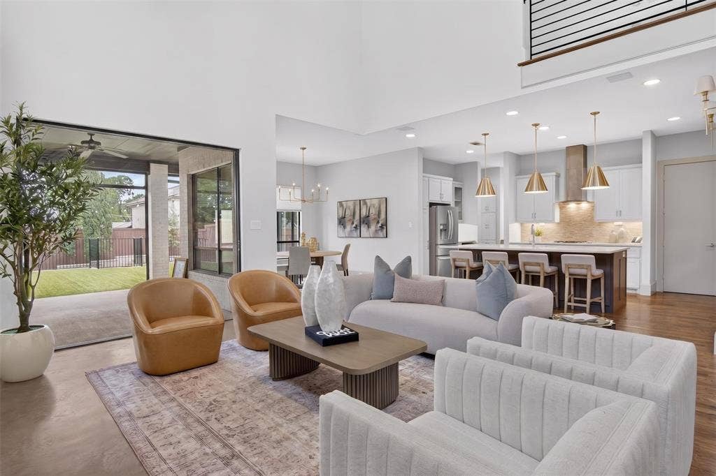 5328 Manett Street, Dallas, TX 75206 Open-concept living area with high ceilings, wood-finish flooring, and a contemporary kitchen featuring a large island, pendant lighting, and stainless steel appliances