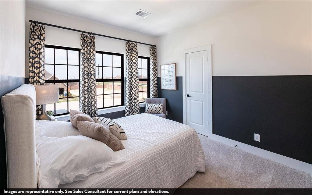 810 Metcalf Drive, Princeton, TX 75071 Three large windows with black frames, two-tone wall treatment, and white interior door with black hardware