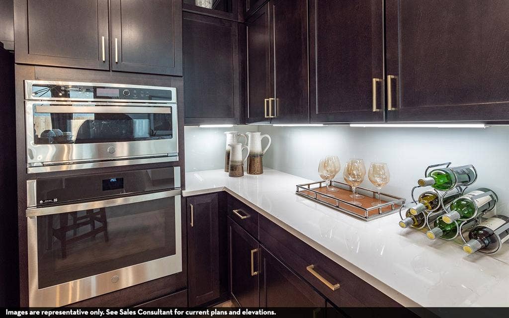 810 Metcalf Drive, Princeton, TX 75071 Dark wood-finish cabinetry with gold-tone hardware, white countertops, built-in stainless steel microwave, and built-in stainless steel oven