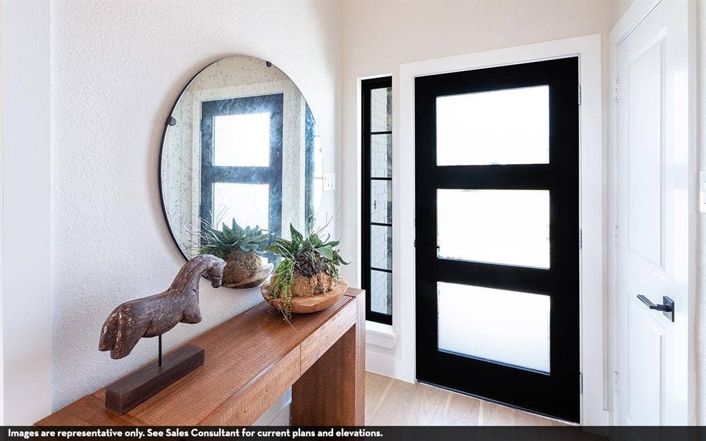810 Metcalf Drive, Princeton, TX 75071 Warm wood-finish console table, round wall-mounted mirror, and sleek black entry door with frosted glass panels