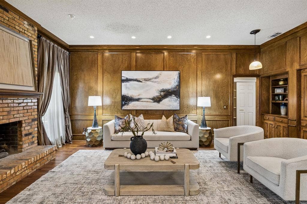 The living room has handsome paneled walls, wood floors and a fireplace with a gas starter.