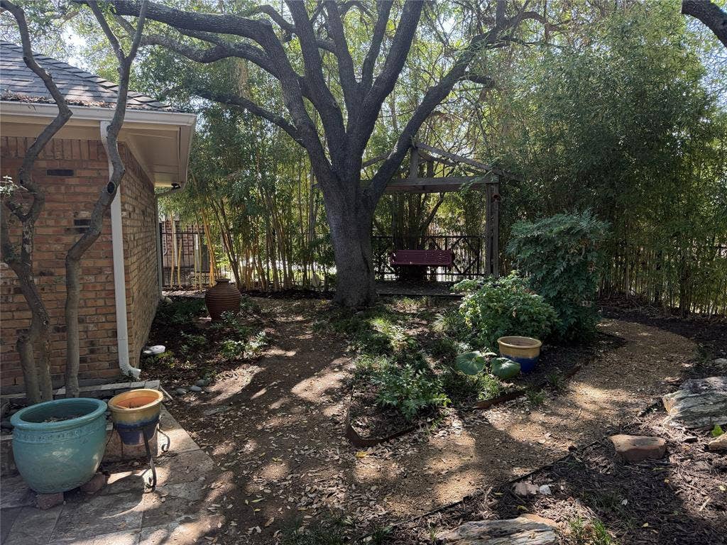 The wooden pergola offers a place to swing and enjoy the peaceful beauty of the yard.